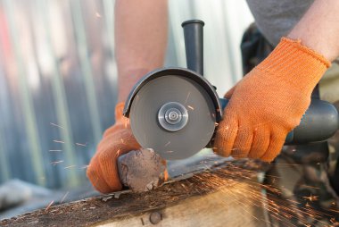 Bir adam metal elektrikli testere ile keser..