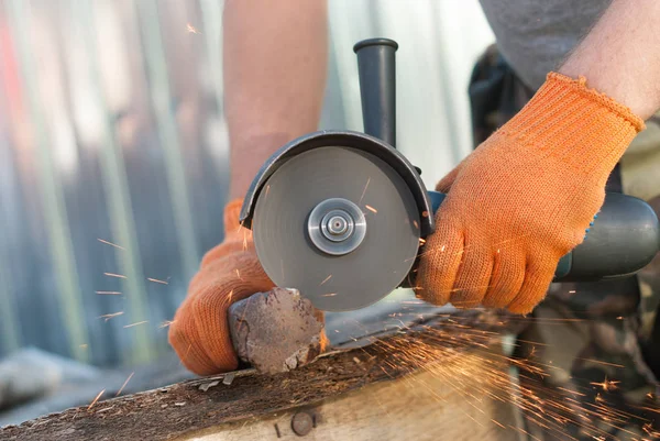 Bir adam metal elektrikli testere ile keser..