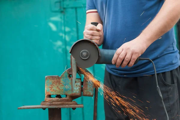 Le travailleur coupe une bande de métal, tenue à la main par une scie électrique . — Photo