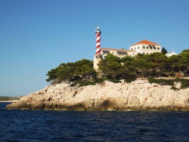 Güneşli bir uçurumun kenarında üzerinde eski bir deniz feneri                          