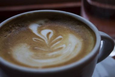 Yakın sıcak, taze kahverengi kahve çubuğunda ahşap bir masa üzerinde güzel çizim ile | barista | sanat