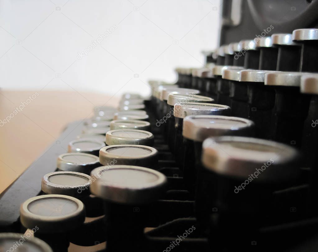  An old,black type machine on brown wooden table and white background                                                            