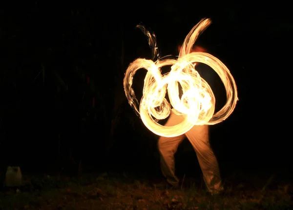 Una bailarina de fuego gira fuego sobre bolas con cadenas (poi) en la playa — Foto de Stock