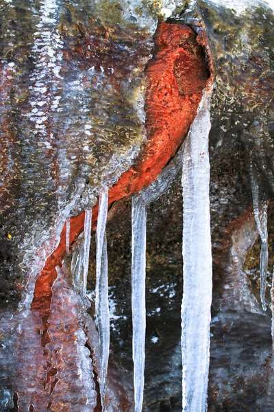 Icicles hang off of a rock wall colored orange by minerals in the Tongariro National Park, Nueva Zelanda — Foto de Stock