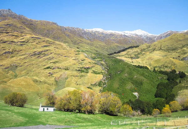 A small house beneath large hills in the Matukituki Valley on New Zealand's south island