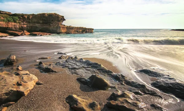 Larga exposición de olas que fluyen sobre una playa rocosa en Pancake Rocks en la isla sur de Nueva Zelanda — Foto de Stock