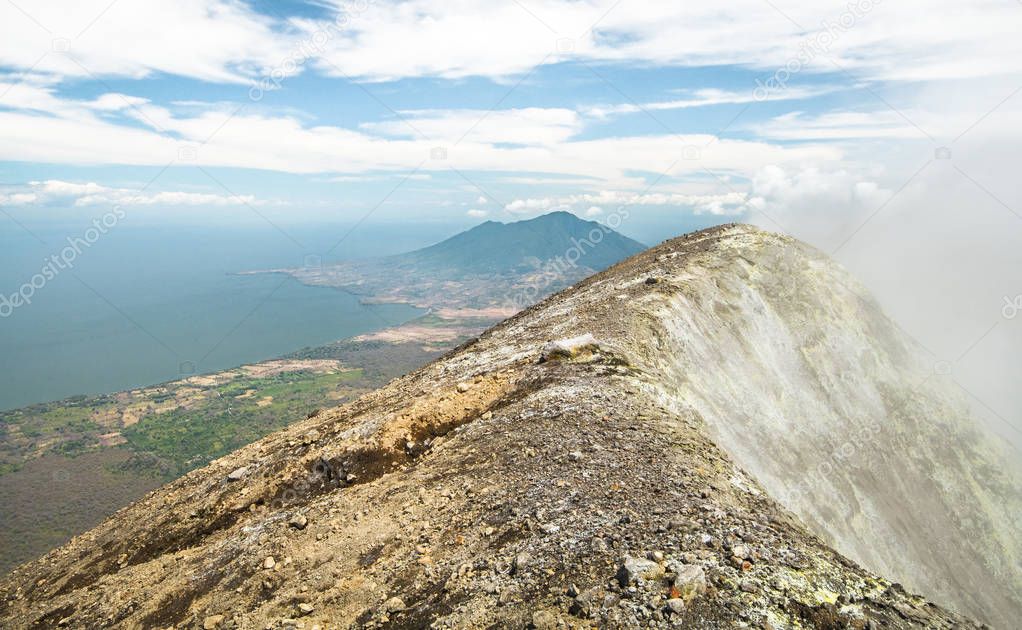 Gases and fumes spew out of the crater at the peak of Volcan Concepcion on Ometepe, Nicaragua. In the distance, Volcan Madera rises above the horizon