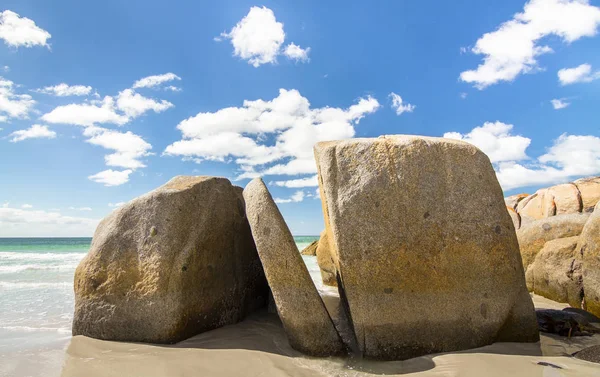 Una gran losa de roca se encuentra en diagonal en un espacio entre dos grandes rocas en una playa de arena blanca. Bahía de los Fuegos, Tasmania — Foto de Stock