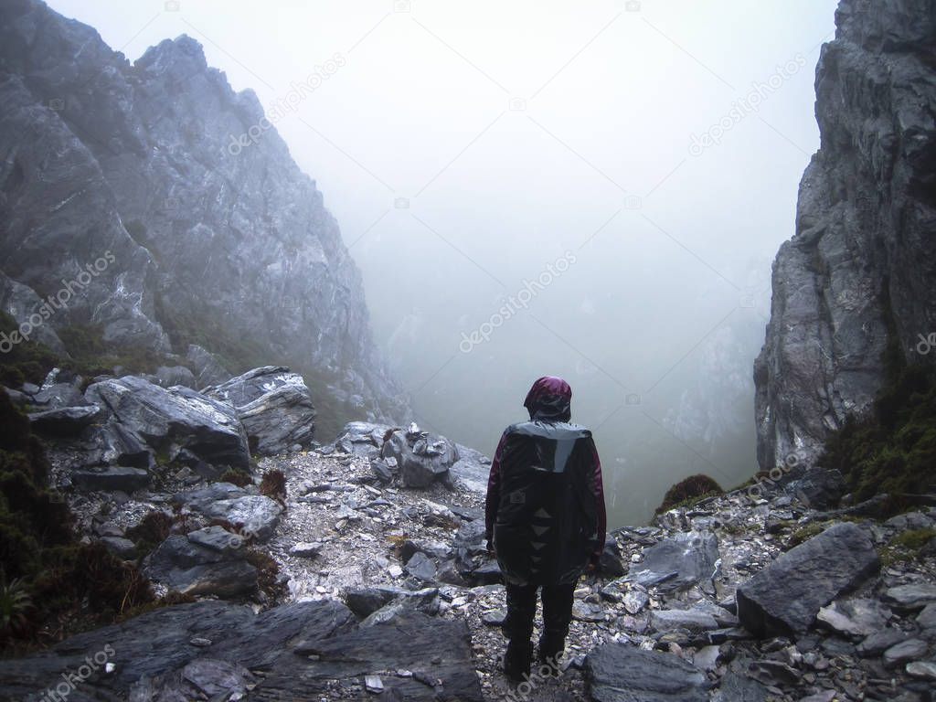 A hiker peers down a steep rocky gully in the Western Arthurs, Tasmania