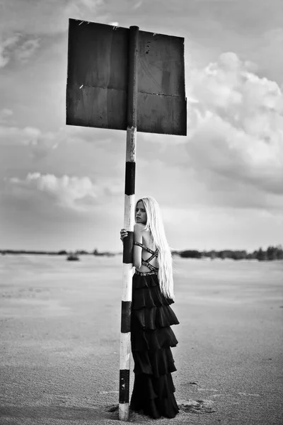 Ξανθιά Κοπέλα Στο Μακρύ Μαύρο Φόρεμα Στην Έρημο Ένα Πανό — Φωτογραφία Αρχείου