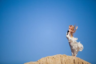 denizin kenarında uzun beyaz elbiseli gelin