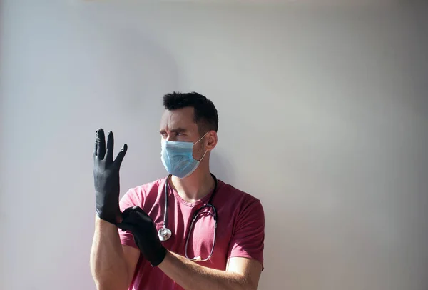 Koruyucu maskeli bir adam eldiven giyer. Dünyada Coronavirus