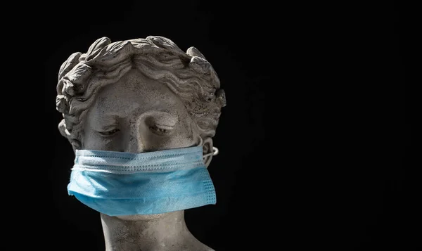 Italian statue in protective blue mask on black background