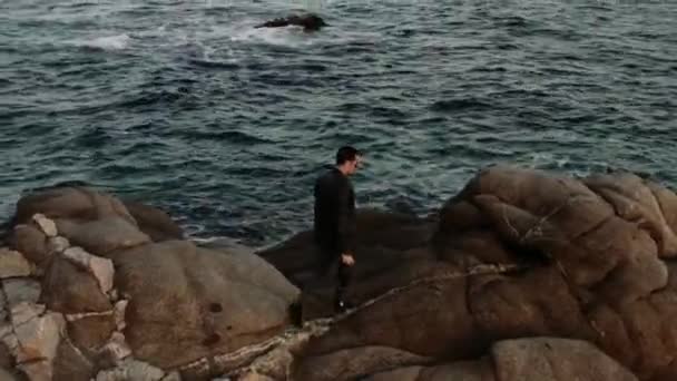 Man Black Leather Jacket Walks Cliff Camera His Hand Shooting — Stock Video