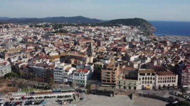 Top view 'den çekilen deniz ve dağların yanındaki küçük bir Avrupa kasabası. Merkezinde yüksek çan kulesi olan bir kilise var.