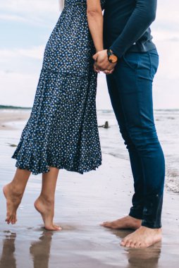 Kumsalda el ele tutuşan bir çift.