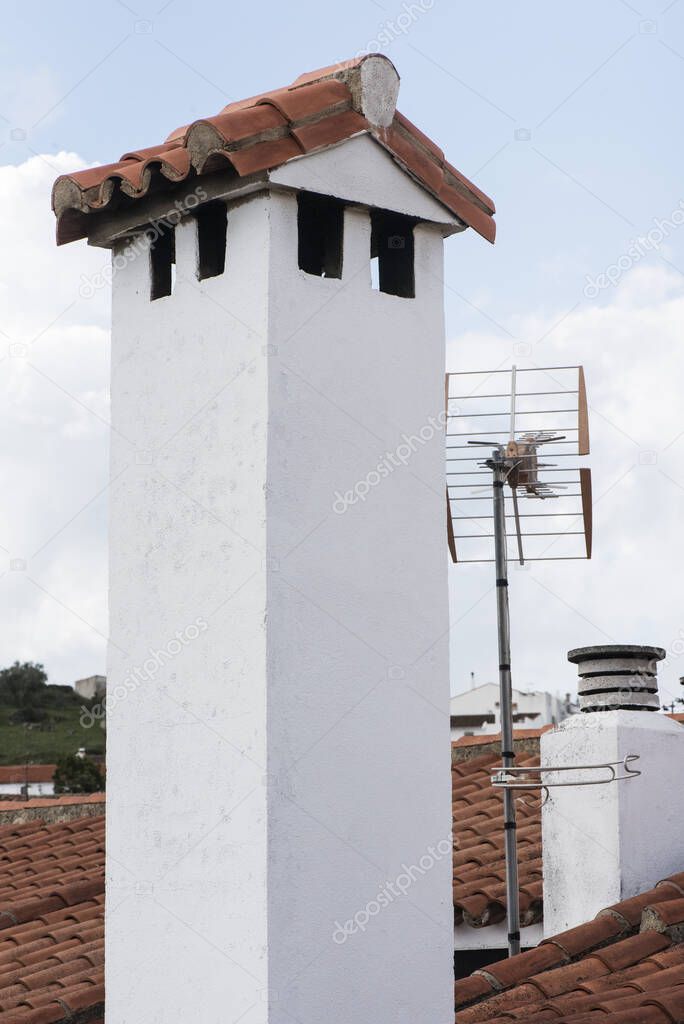 White painted village chimneys with lime television antennas and red clay tile roofs natural daylight