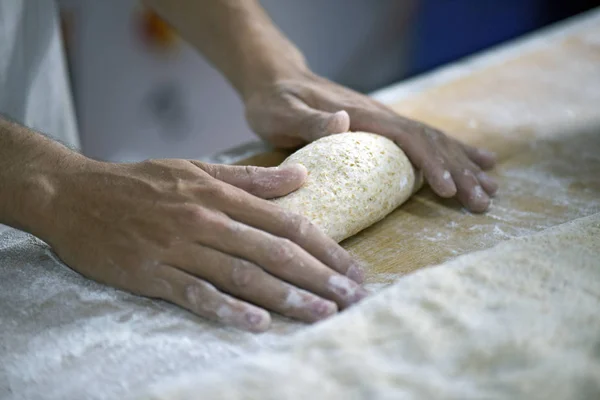 Hand of baker molding breads for baking