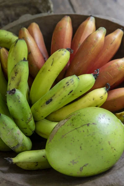 Wooden tray with two types of bananas and calabash fruit on a farmhouse table. Brazil