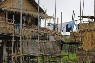 Burma, Inle Gölü 'ndeki Nyaung Shwe kasabasında su birikintilerinin üzerinde duran basit bombalı ev, ipte kurumuş giysiler.