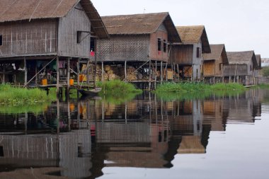 Birmanya 'daki Inle Gölü' nde su üzerinde duran bambu evler, durgun sulardaki evlerin yansıması.