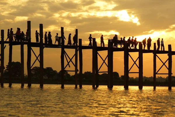 Silueta negra de madera de teca U Bein Bridge y personas que caminan sobre el fondo del cielo nublado naranja al atardecer, Birmania — Foto de Stock