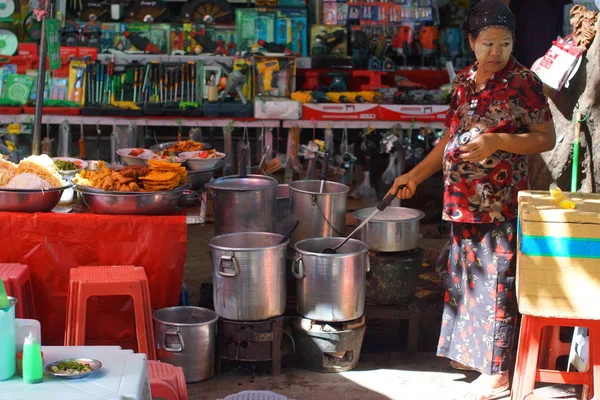 Yangon, Burma Myanmar - 9 Kasım 2012. Birmanyalı kadın sokakta büyük kaplarda geleneksel yemekler pişiriyor.