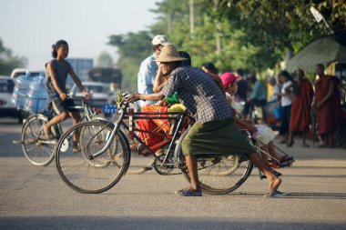 Yangon, Burma - 29 Kasım 2012. Birmanyalı uzun etekli adam eski bisikletle sokağa çıkıyor. Birmanya sokak hayatı