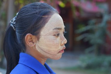 Bagan, Burma Myanmar - 3 Aralık 2012. Yüzünde Thanaka kozmetik olan Birmanyalı genç kızın yan portresi.