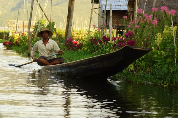 Nyaungshwe on Inle Lake, Birmania - 4 de diciembre de 2012. Hombre birmano sentado en un barco tradicional de madera, remando en el lago — Foto de Stock