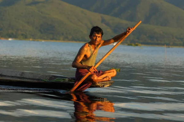 Nyaung Shwe, Inle Gölü, Burma - 4 Aralık 2012. Birmanyalı adam geleneksel ahşap teknede oturuyor ve gölde kürek çekiyor.