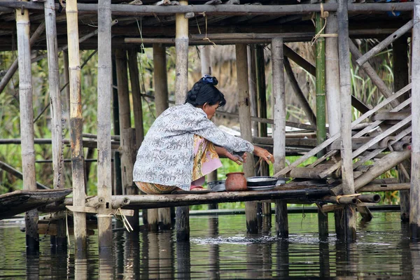 Nyaungshwe Lago Inle, Birmania - 4 de diciembre de 2012. mujer lavar los platos en agua del lago en la escalera de la casa de bambú en pilas — Foto de Stock