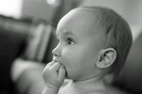 Black and white side portrait of little pensive child holding hand near face, closeup face with big eyes