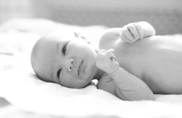 Schwarz-weißes Porträt eines kleinen Neugeborenen, das nebenbei im Babybett zu Hause liegt. Kleines süßes Baby, Nahaufnahme — Stockfoto