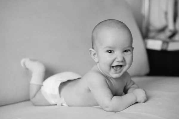 Black and white portrait of little smiling newborn baby. Cute happy baby lying on stomach and laughing, closeup — Stock Photo, Image