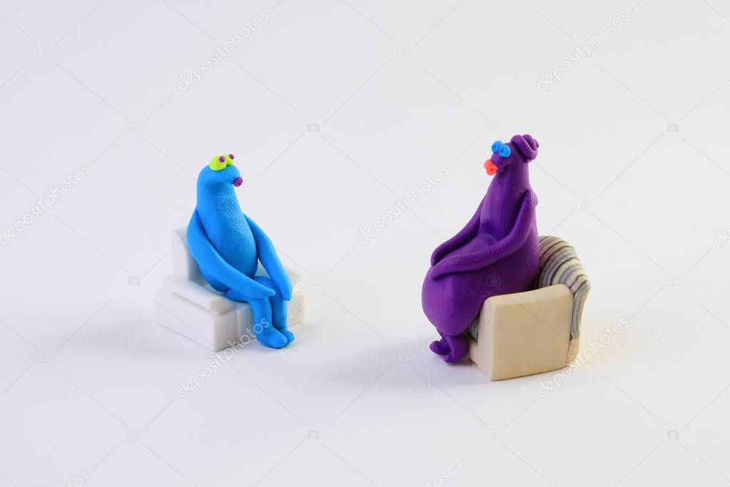 Colorful Plasticine figurines sitting on sofas, psychological therapy concept