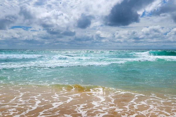 Den sandfylte stranden i det tropiske havet og den overskyede himmelen. . – stockfoto