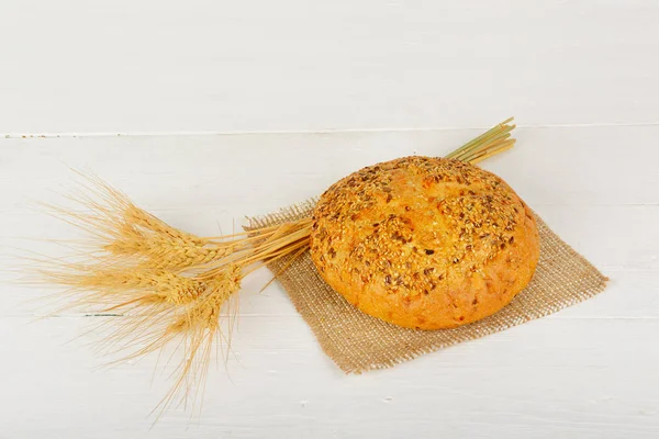 焼きたてのパンと木製のテーブルの上の小麦。テキスト用の空き容量. — ストック写真