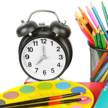 Alarm saati, renkli kalem seti ve suluboya izole eder