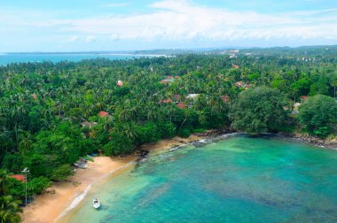 Zengin mavi tonlarda deniz pelerini. Parlak turkuaz su ve tropikal bitki örtüsü olan güzel bir plaj..