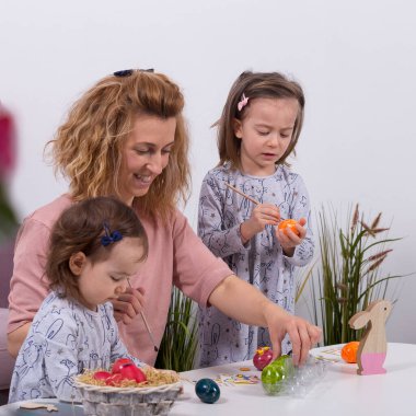 Anne ve kızları yumurta boyuyor. Mutlu aile Paskalya için hazırlanıyor. Evde karantina.