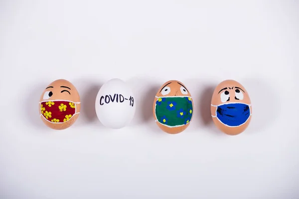 Tıbbi maske takan, karalama yüzlü çeşitli tavuk yumurtaları. Corona virüs salgını sırasındaki Paskalya 'nın kavramsal görüntüsü. Evde karantina