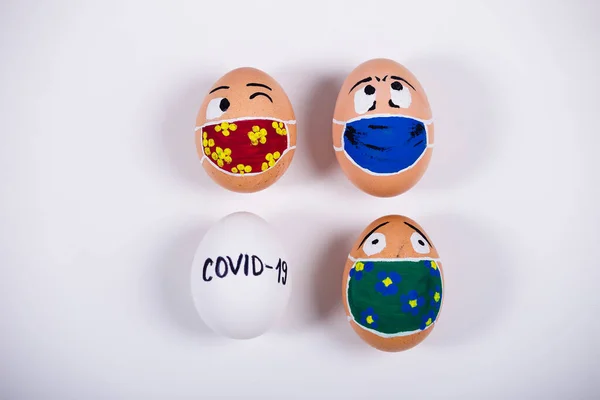 Tıbbi maske takan, karalama yüzlü çeşitli tavuk yumurtaları. Corona virüs salgını sırasındaki Paskalya 'nın kavramsal görüntüsü. Evde karantina.