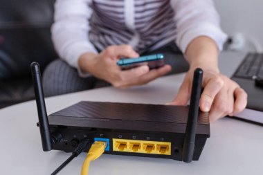 Wi-Fi yönlendirici ve akıllı telefonu evdeki oturma odasında kullanan bir kadın.