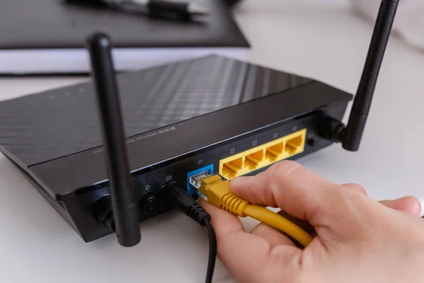 woman connects the internet cable to the router\'s socket. Fast and wireless internet concep