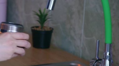 Mutfak lavabosundan kahve kazanına su koyan bir kadının el görüntüsünü kapat.
