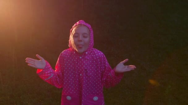 雨の中で幸せな女の子が遊んでいて楽しさがあるのでうれしいです 自然への自由と愛の印として腕を開き — ストック動画