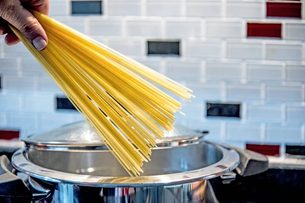 Spagetti yemek pişirmek için tutan el