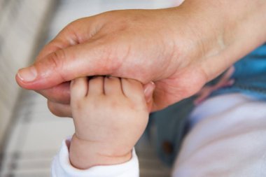 Genç bir kadının elini tutarak küçük bebek