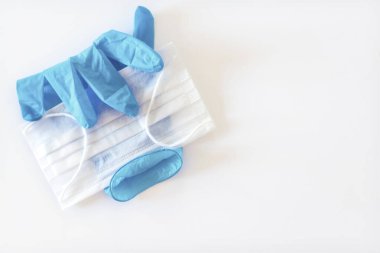 Tek mavi lateks eldiven ve beyaz arka planda beyaz bir maske, yakın çekim, izole edilmiş.
